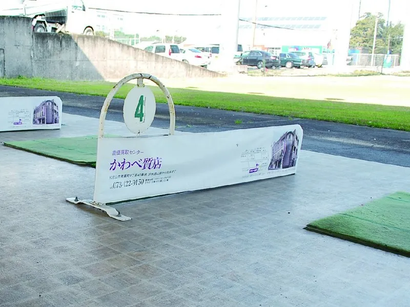 ゴルフ場の打席の間仕切りに設置した質屋の広告